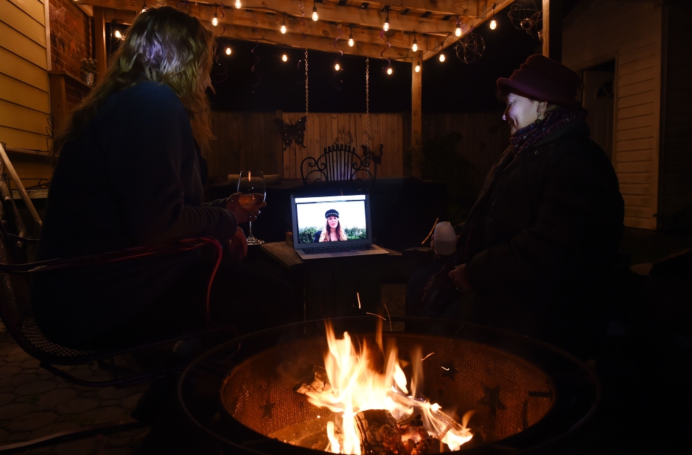 Neighbors sit around a fire-pit to watch Beyonce perform during the 