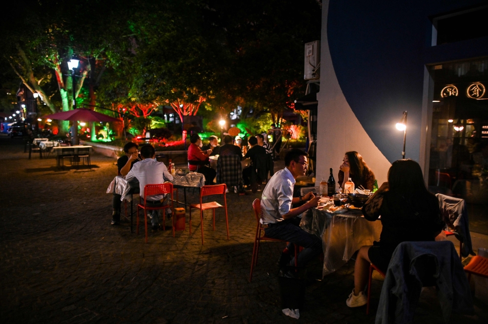 :People eat outdoor next to a restaurant in Wuhan, in China's central Hubei province on April 16, 2020. China has largely brought the coronavirus under control within its borders since the outbreak first emerged in the city of Wuhan late last year. / AFP 