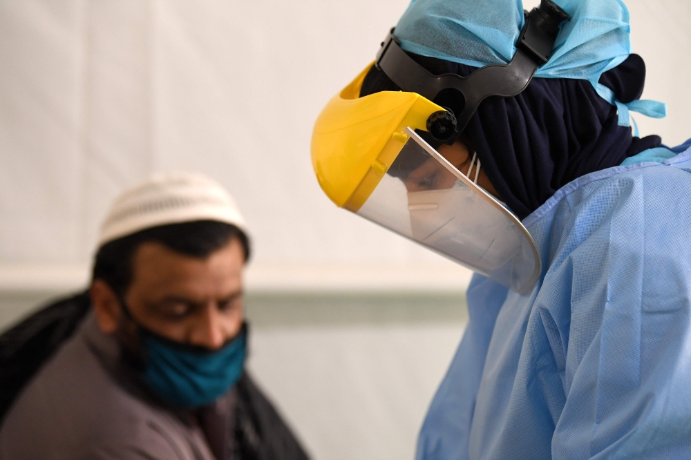 A health worker takes samples from foreign workers to check for the novel coronavirus at a testing centre in the Al Quaz area of Dubai, in the United Arab Emirates, on April 18, 2020. AFP / KARIM SAHIB