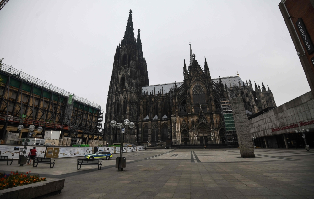 A police car is seen on the almost empty square in front of the Cologne cathedral in Cologne, western Germany, on April 19, 2020, amid the novel coronavirus COVID-19 pandemic. / AFP / Ina FASSBENDER