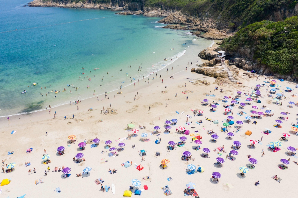 This aerial photo shows people gathering at a beach in Hong Kong on April 19, 2020. Starting on March 29 the city's government banned public gatherings of more than four people in an effort to curb the spread of the COVID-19 coronavirus. / AFP / Dale DE L