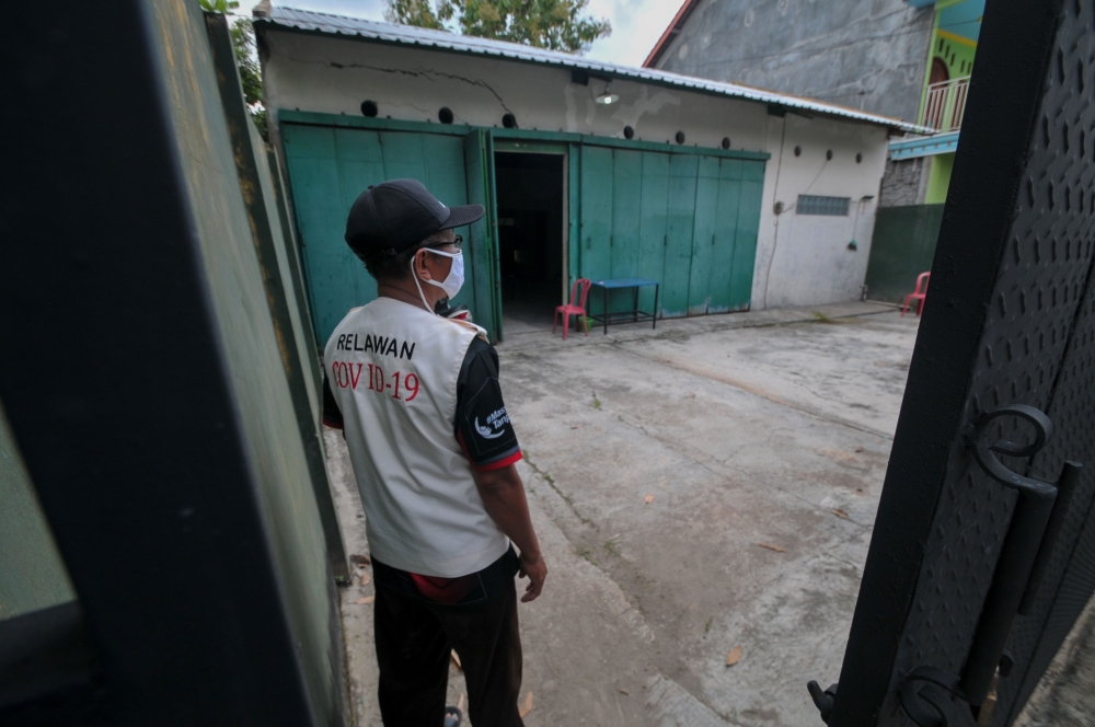 A volunteer looks on at a quarantine facility, a repurposed abandoned house believed by some locals to be haunted and used as a deterrent effect against those breaking social restrictions amid the COVID-19 coronavirus pandemic, at Sepat village in Sragen,