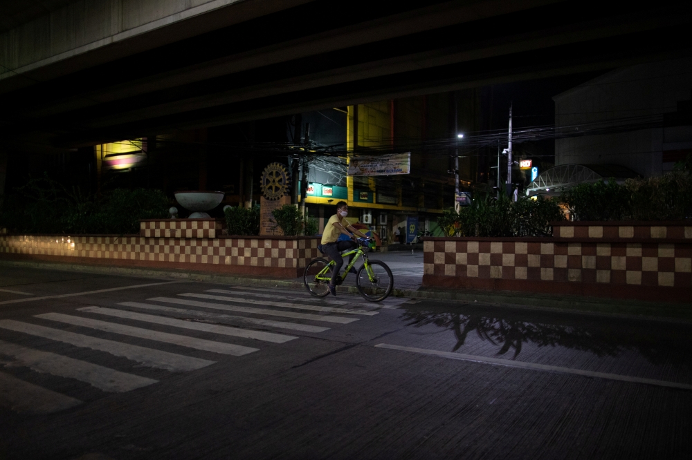 A man wearing a protective face mask rides a bike along an empty road amid the lockdown to contain the coronavirus disease (COVID-19) outbreak in Metro Manila, Philippines, April 21, 2020. REUTERS/Eloisa Lopez