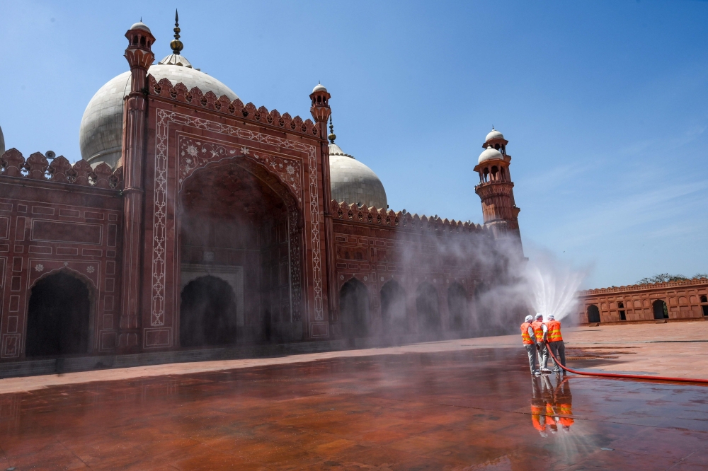 Municipal workers spray disinfectant at the main entrance of the Badshahi mosque ahead of the Muslim holy month of Ramadan during a government-imposed nationwide lockdown as a preventive measure against the COVID-19 coronavirus, in Lahore on April 22, 202