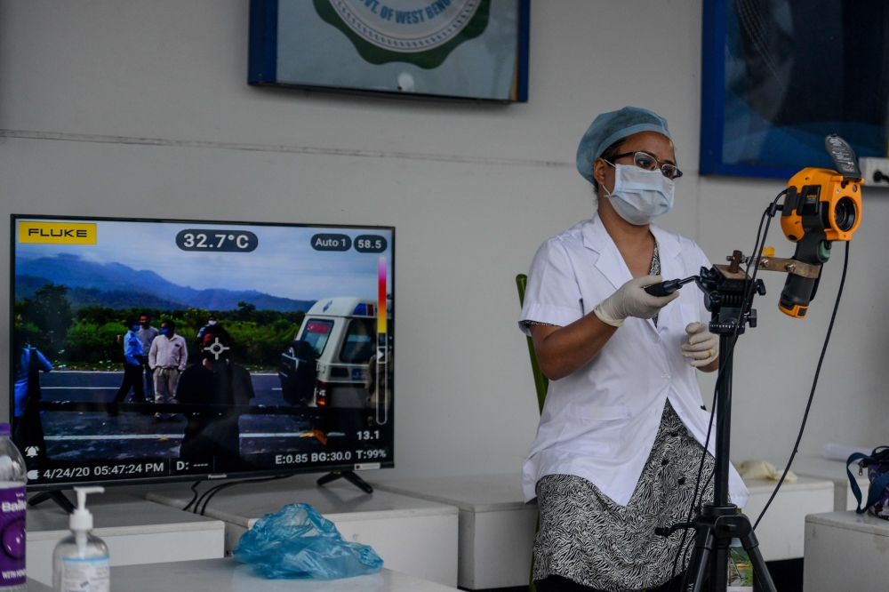 A medical staff uses a thermal scanner at an information collection and awareness desk set up by the West Bengal Health Department of Darjeeling district during a government-imposed nationwide lockdown as a preventive measure against the COVID-19 coronavi