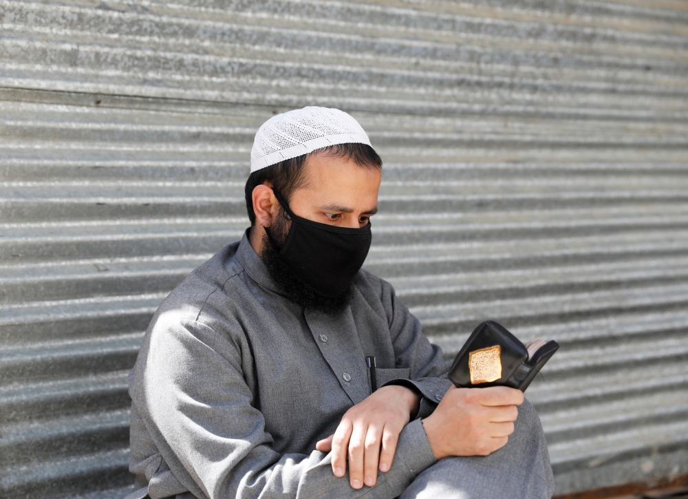 An Afghan man reads the Koran on the first day of the holy fasting month of Ramadan, amid the spread of the coronavirus disease (COVID-19), in Kabul, Afghanistan April 24, 2020. REUTERS/Mohammad Ismail