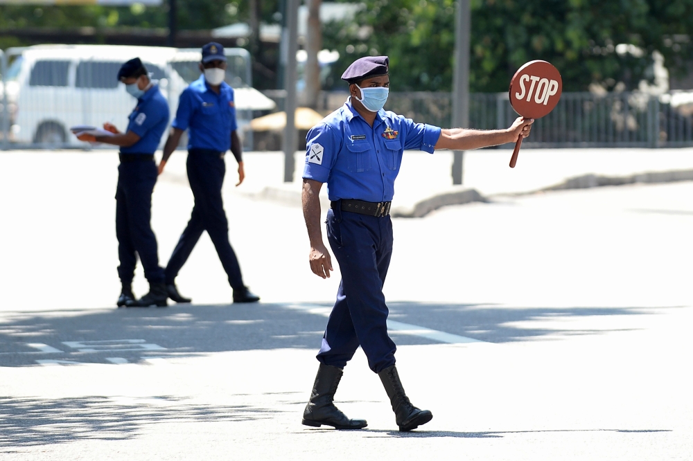 A Sri Lankan Navy personnel (C) wearing a facemask holds a stop sign at a checkpoint during a government-imposed nationwide lockdown as a preventive measure against the COVID-19 coronavirus, in Colombo on April 26, 2020. / AFP / LAKRUWAN WANNIARACHCHI
