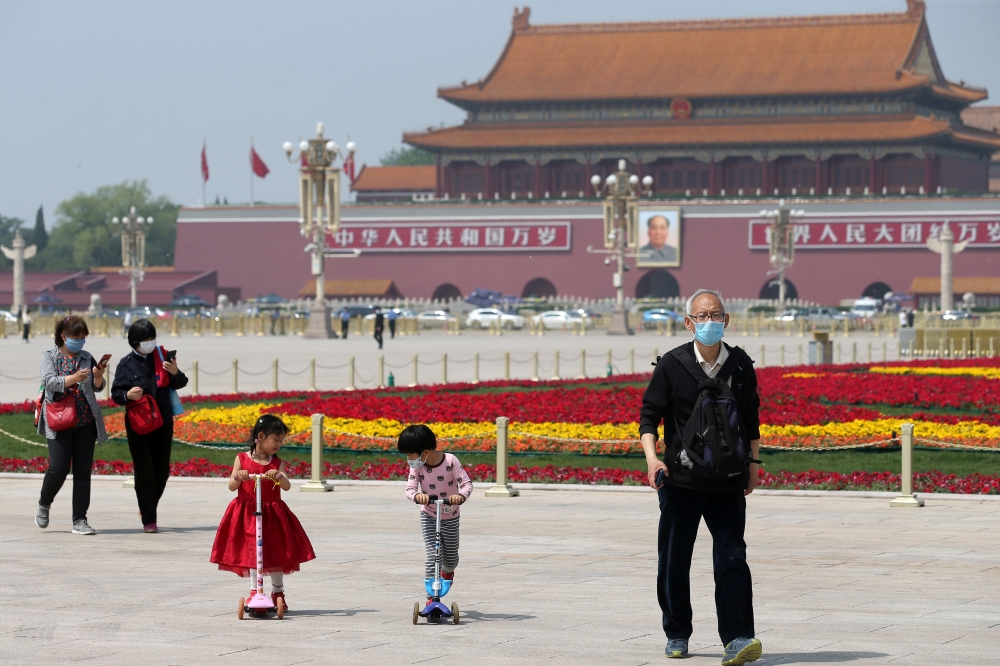 People wearing face masks following the coronavirus disease (COVID-19) outbreak walk past flower installations set up to mark the upcoming Labour Day holiday, at Tiananmen Square in Beijing, China April 29, 2020. 