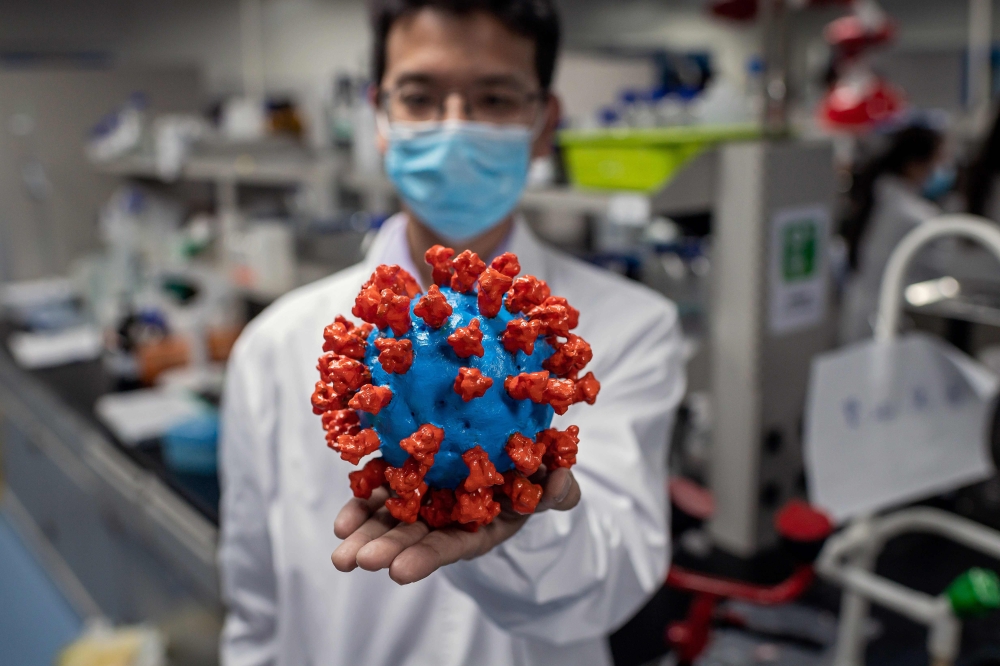 TOPSHOT - In this picture taken on April 29, 2020, an engineer shows a plastic model of the COVID-19 coronavirus at the Quality Control Laboratory at the Sinovac Biotech facilities in Beijing. AFP / NICOLAS ASFOURI / 