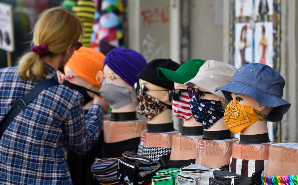 A woman checks out face covers on display outside a clothing store in Berlin on April 28, 2020 amid the new coronavirus COVID-19 pandemic.  AFP / John MACDOUGALL