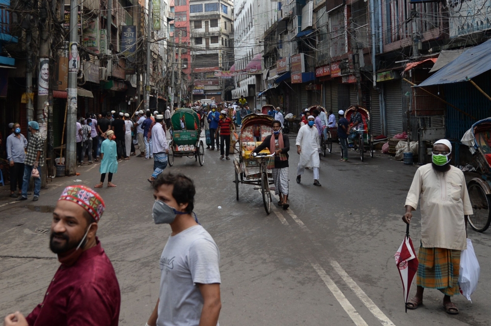People walk on an empty street usually busy with stalls selling traditional food for Iftar, the breaking fast of Muslim's holy fasting month of Ramadan, during a government-imposed lockdown as a preventative measure against the spread of the COVID-19 coro