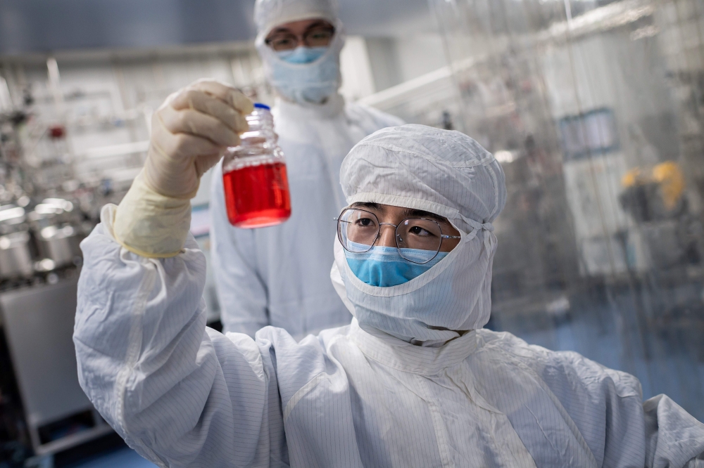 TOPSHOT - In this picture taken on April 29, 2020, an engineer looks at monkey kidney cells as he make a test on an experimental vaccine for the COVID-19 coronavirus inside the Cells Culture Room laboratory at the Sinovac Biotech facilities in Beijing. / 
