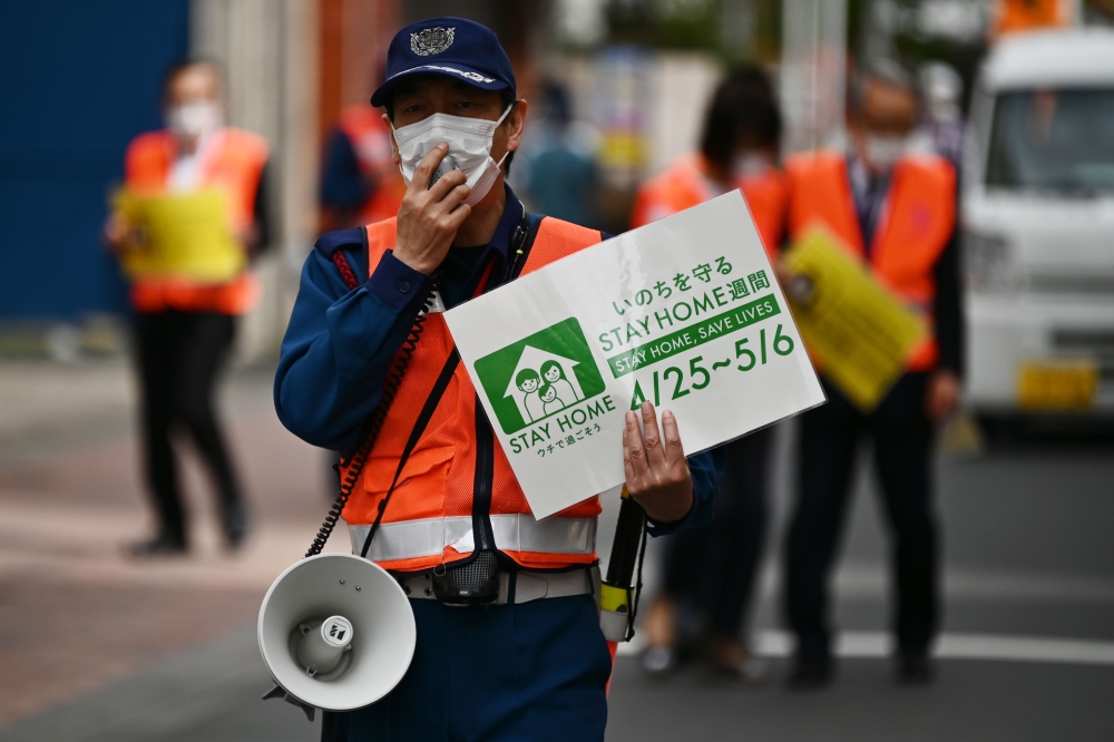 Municipal employees patrol a street asking people to stay home amid the COVID-19 coronavirus outbreak in Tokyo on May 4, 2020. AFP / CHARLY TRIBALLEAU