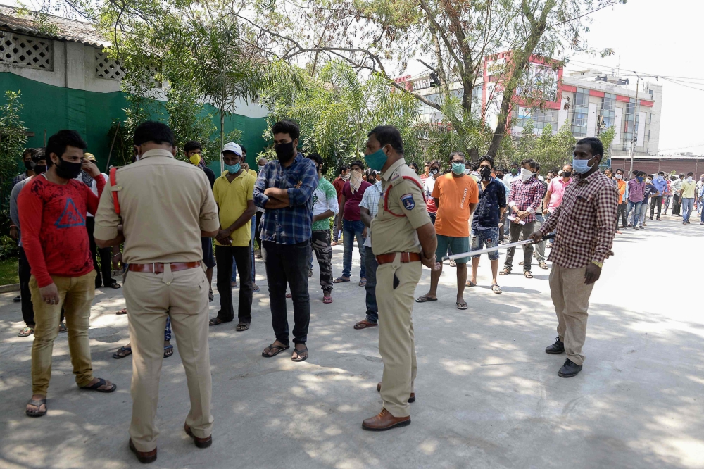 Police personnel register migrant workers to send them back to their hometowns during a government-imposed nationwide lockdown as a preventive measure against the COVID-19 coronavirus, on the outskirts of Hyderabad on May 4, 2020. / AFP / NOAH SEELAM