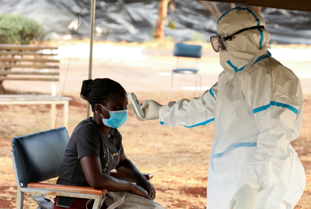 A woman has her temperature checked by a healthcare worker during a nationwide lockdown to help curb the spread of the coronavirus disease (COVID-19), at a mass screening and testing centre, in Harare, Zimbabwe April 30, 2020. REUTERS/Philimon Bulawayo