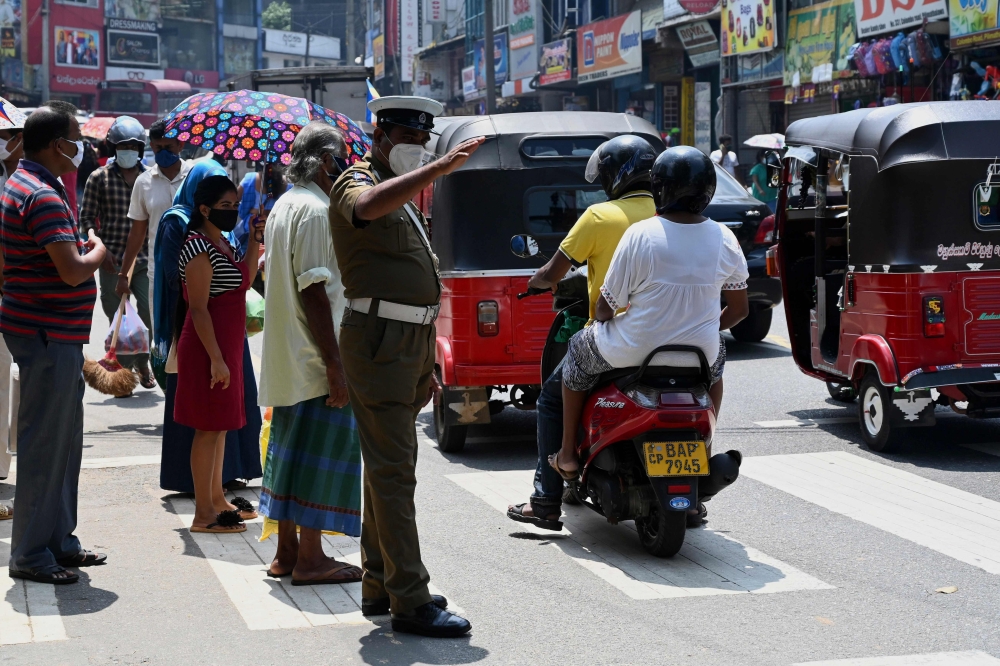 A police officer directs traffic on a road in the central Sri Lankan town of Pilimathalawa May 5, 2020, during a break in the curfew that was first imposed on March 20. AFP / Ishara S. KODIKARA
