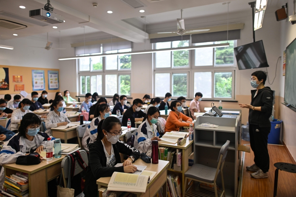 Students wearing face masks are seen in their classroom during a government-organised media tour at Shanghai High School after it reopened in Shanghai on May 7, 2020.   AFP / Hector RETAMAL
