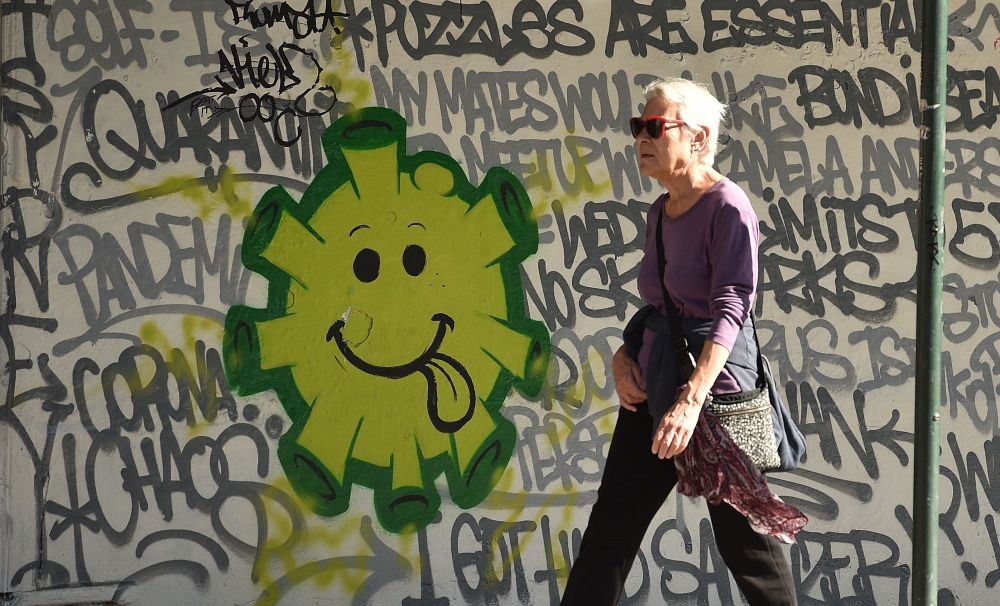 A woman walks past a street art in Sydney on May 8, 2020. Australia's government unveiled a three-stage plan to get the economy back to a new 