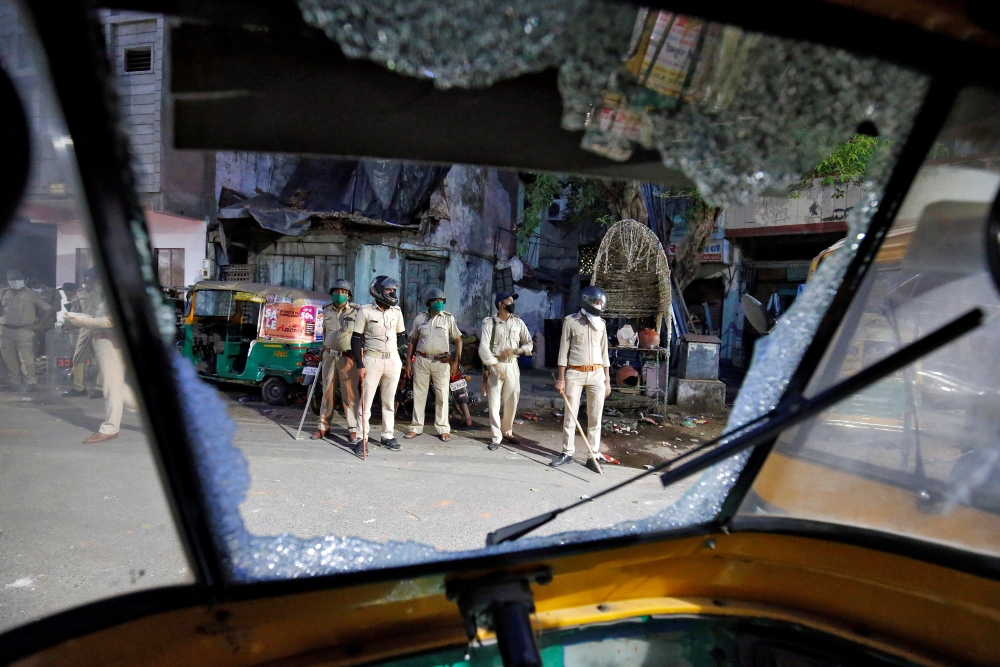 Policemen are seen through a broken windshield of an auto-rickshaw during clashes with police after police urged the residents to remain indoors during an extended lockdown to slow the spreading of the coronavirus disease (COVID-19), in Ahmedabad, India, 