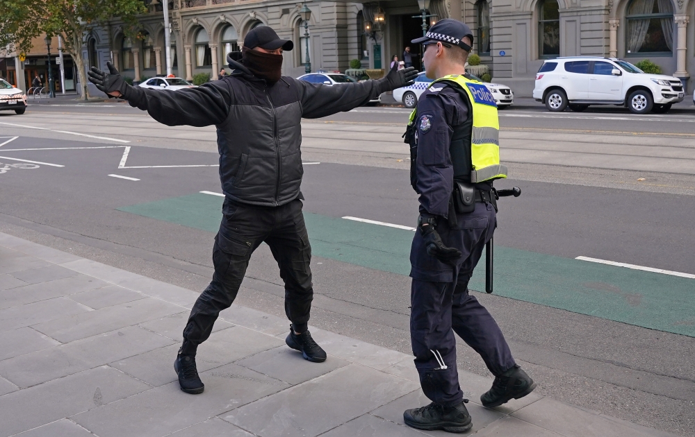 A police officer approaches a protester opposing lockdown measures implemented to curb the spread of the coronavirus disease (COVID-19) outside Parliament House in Melbourne, Australia, May 10, 2020. AAP Image/Scott Barbour via REUTERS 