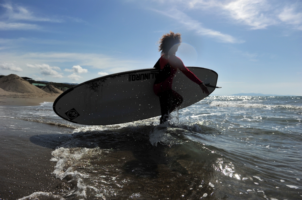 A surfer walks into the water as Italy begins to ease some of the restrictions of the coronavirus disease (COVID-19) lockdown, in Castiglione della Pescaia, Italy May 9, 2020. REUTERS/Jennifer Lorenzini