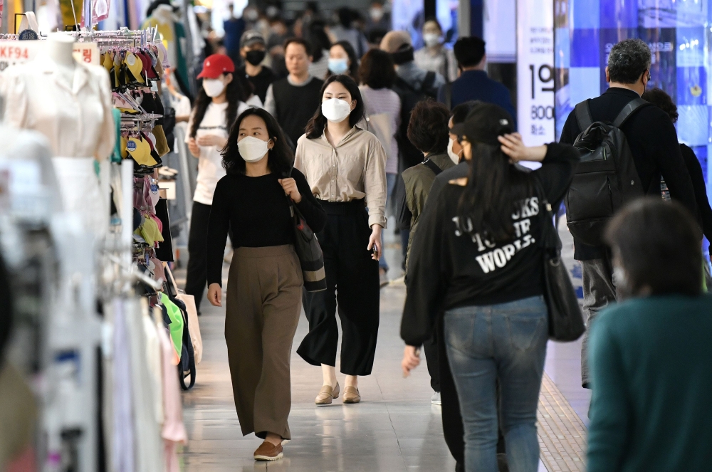 People wearing face masks walk through an underground shopping area in Seoul on May 6, 2020. South Korea returned largely to normal on May 6 as workers went back to offices, and museums and libraries reopened under eased social distancing rules after new 