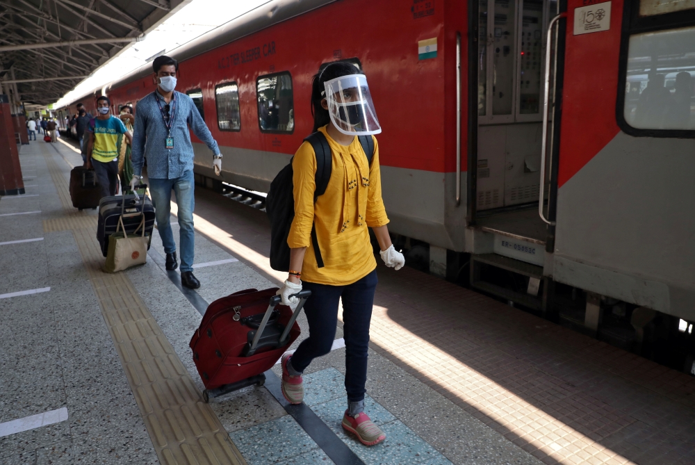 People with their luggage walk to board a train that will take them to New Delhi after India announced a limited reopening of its giant rail network following a nearly seven-week lockdown to slow the spreading of the coronavirus disease (COVID-19), at the