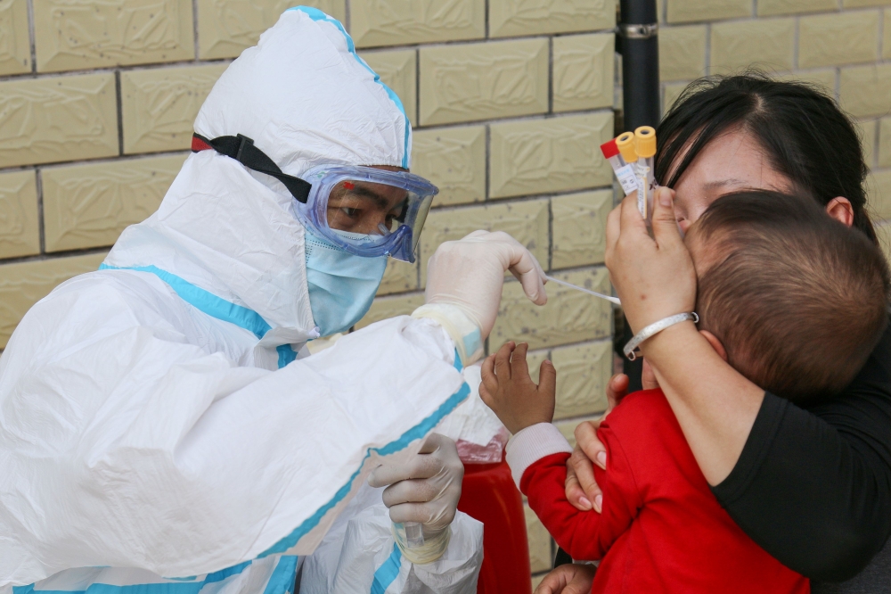 A medical staff member takes a swab sample from a child to test for the COVID-19 novel coronavirus in Jian in China's central Jiangxi province on May 13, 2020. China OUT / AFP / STR
