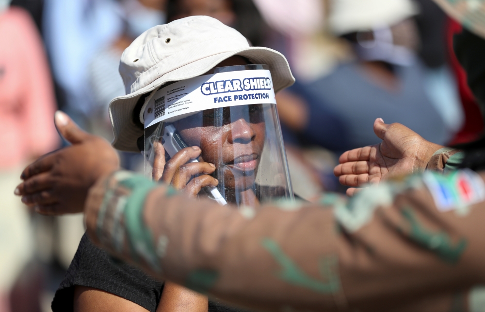 A woman wears a protective face shield during food distribution, as South Africa starts to relax some aspects of a stringent nationwide coronavirus disease (COVID-19) lockdown, in Diepsloot near Johannesburg, South Africa, May 8, 2020. REUTERS/Siphiwe Sib