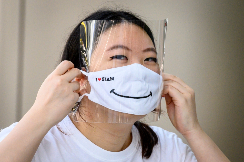 :An employee puts on a mask and a face shield at the Siam Paragon shopping mall as it reopened after restrictions to halt the spread of the COVID-19 coronavirus were lifted in Bangkok on May 17, 2020. / AFP / Mladen ANTONOV

