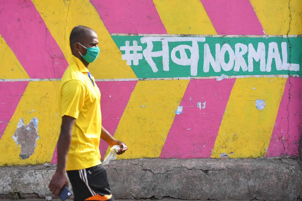 A pedestrian walks past a wall graffiti during a nationwide lockdown imposed as a preventive measure against the spread of the COVID-19 coronavirus, in Mumbai on May 15, 2020. / AFP / INDRANIL MUKHERJEE

