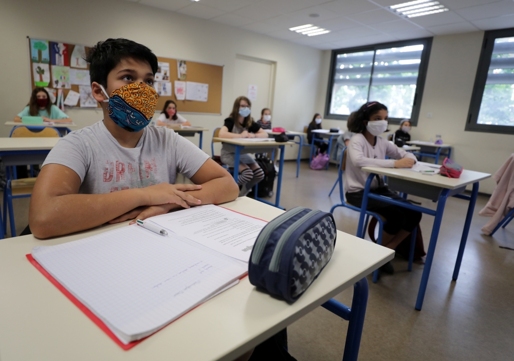 Students, wearing protective face masks, listen to their teacher at the College Sasserno school during its reopening in Nice as a small part of French shoolchildren head back to their schools with new rules and social distancing during the outbreak of the