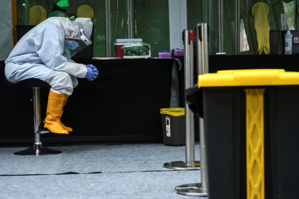 A medical staff member waits to take a swab sample from a citizen amid the coronavirus disease (COVID-19) outbreak, in Jakarta, Indonesia May 20, 2020. Antara Foto/Muhammad Adimaja 
