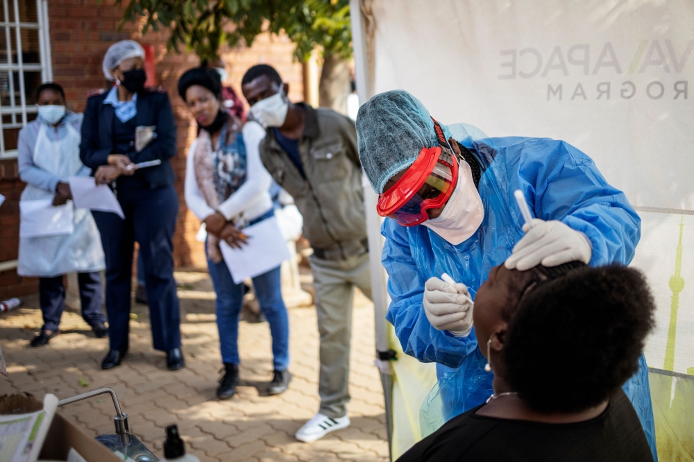 Doctors Without Borders (MSF) nurse Bhelekazi Mdlalose (2nd R), 51, performs a swab test for COVID-19 coronavirus on a health worker at the Vlakfontein Clinic in Lenasia, Johannesburg, on May 13, 2020./ AFP / Michele Spatari
