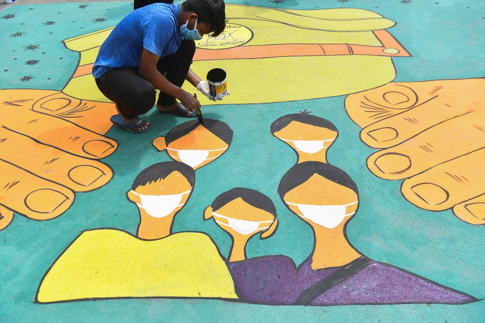 An artist paints a floor mural dedicated to police forces to thank their service braving all risks during a nationwide lockdown to fight the spread of the COVID-19 coronavirus, in Mumbai on May 16, 2020. / AFP / INDRANIL MUKHERJEE
