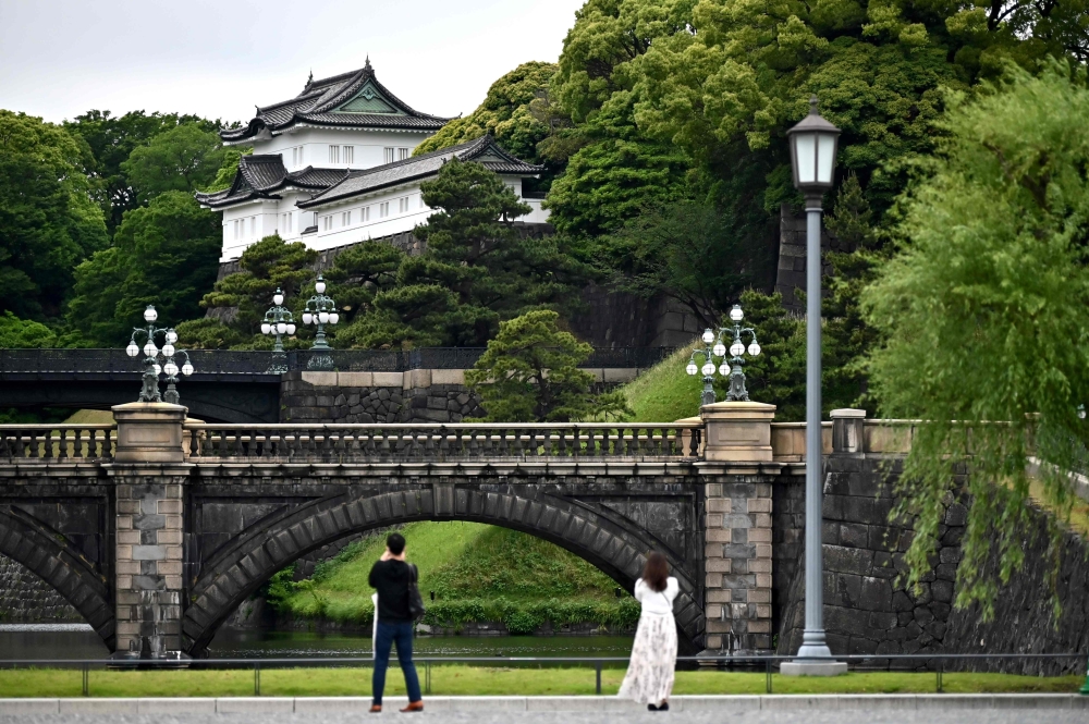 People take pictures of the Imperial Palace, a popular tourist destination, in Tokyo on May 20, 2020. Japan on May 14 lifted a state of emergency imposed due to the coronavirus for the majority of the country but kept it in place for top cities Tokyo and 