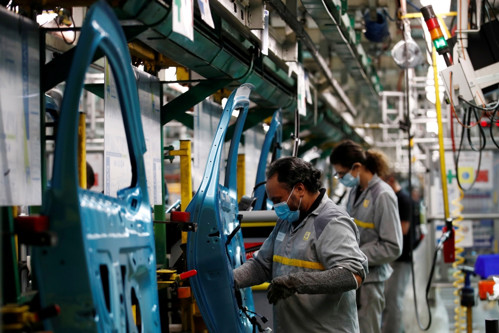 Employees, wearing protective face masks, work on the automobile assembly line of Renault ZOE cars at the Renault automobile factory in Flins as the French carmaker ramps up car production with new security and health measures during the outbreak of the c