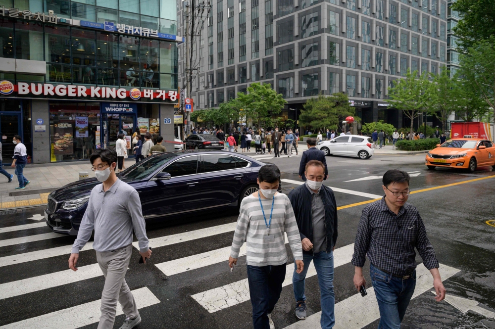 Office workers cross a street during the lunch period in central Seoul on May 22, 2020. / AFP / Ed JONES
