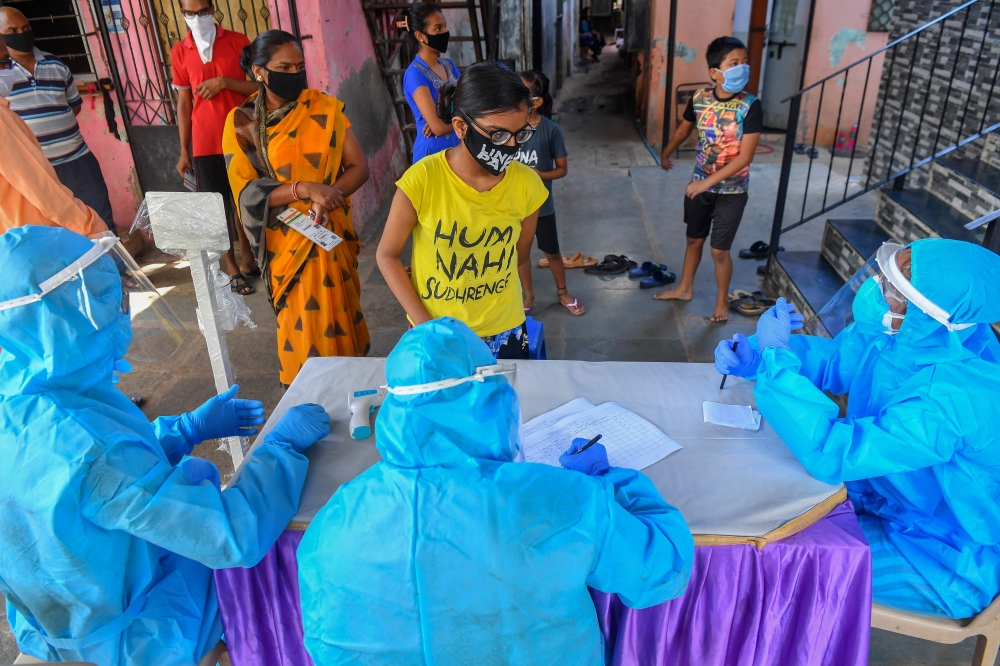 Residents wait for a medical check-up at a screening centre set up inside a slum during a nationwide lockdown to fight the spread of the COVID-19 coronavirus, in Mumbai on May 29, 2020. / AFP / INDRANIL MUKHERJEE