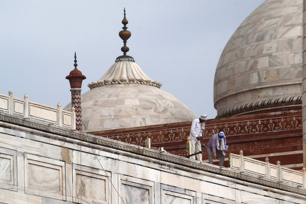 In this picture taken on May 30, 2020, workers stand on the railing of the Taj Mahal after it was damaged due to heavy rainstorm in Agra. / AFP / Pawan Sharma