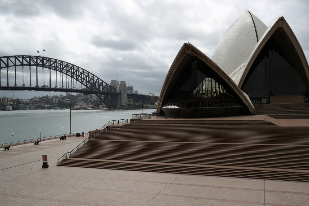 People are seen on the nearly deserted steps of the Sydney Opera House, in the wake of New South Wales in Australia, March 26, 2020. REUTERS/Loren Elliott/File Photo