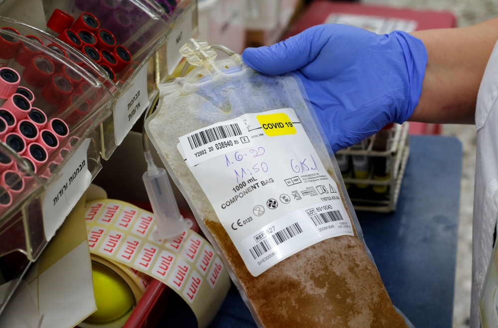 A medical worker at Magen David Adom’s Blood Services holds a plasma sample donated by recovered novel coronavirus patients on June 1, 2020. / AFP / GIL COHEN-MAGEN

