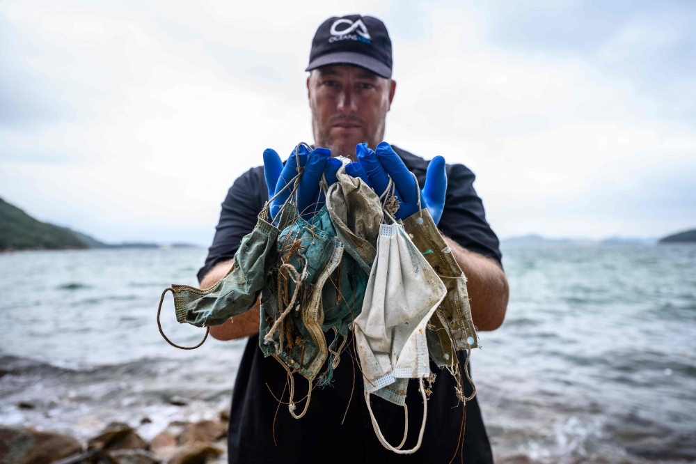 In this photo taken on May 13, 2020, Gary Stokes, founder of the environmental group Oceans Asia, poses with discarded face masks he found on a beach in the residential area of Discovery Bay on the outlying Lantau island in Hong Kong.  / AFP / Anthony WAL