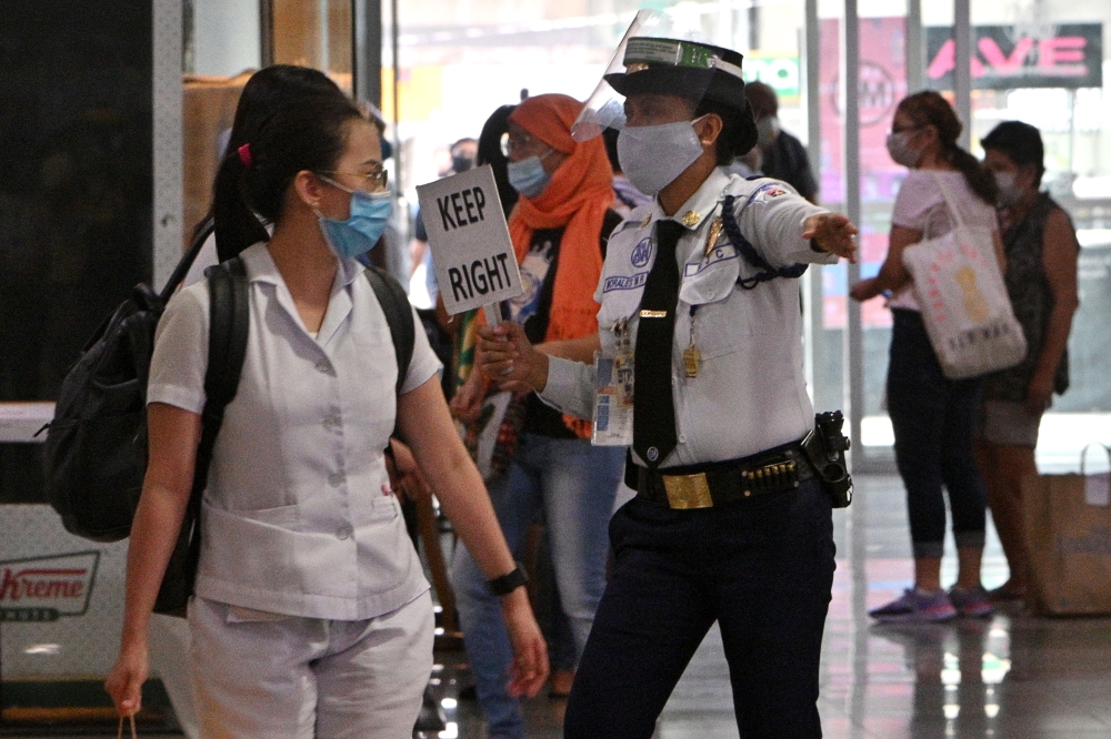 :A guard guides shoppers through a walkway, as part of social distancing measures to prevent the spread of the COVID-19 novel coronavirus, at a mall in Manila on June 2, 2020, a day after the government eased up quarantine measures in the country's capita