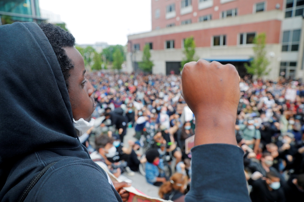 FILE PHOTO: Demonstrators raise their fists as they take a knee for 8 minutes 46 seconds, the length of time George Floyd was held down with a knee on his neck by a Minneapolis Police officer, during a protest against racial inequality in the aftermath of