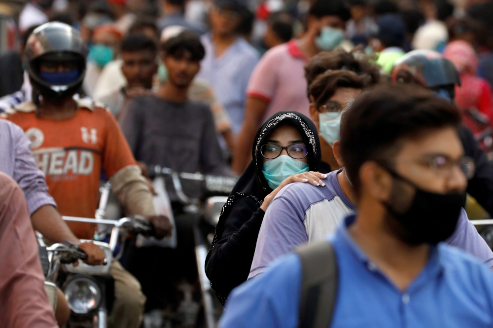 FILE PHOTO: A woman rides on a motor bike as she wears a protective face mask amid the rush of people outside a market as the outbreak of the coronavirus disease (COVID-19) continues, in Karachi, Pakistan June 8, 2020. REUTERS/Akhtar Soomro/File Photo
