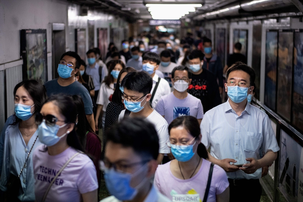 People wearing face masks walk in a subway station during morning rush hour in Beijing on June 8, 2020. / AFP / NOEL CELIS

