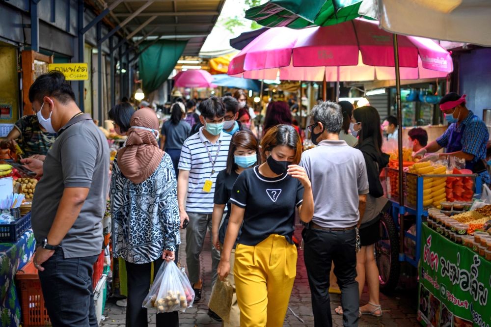 People walk in a street food market in Bangkok on June 9, 2020. / AFP / Mladen ANTONOV