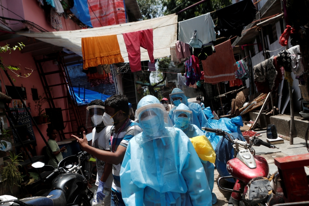 Healthcare workers wearing personal protective equipment (PPE) and volunteers walk through a slum in Dharavi, one of Asia's largest slums, to check residents during a lockdown to slow the spread of the coronavirus disease (COVID-19), in Mumbai, India, Jun