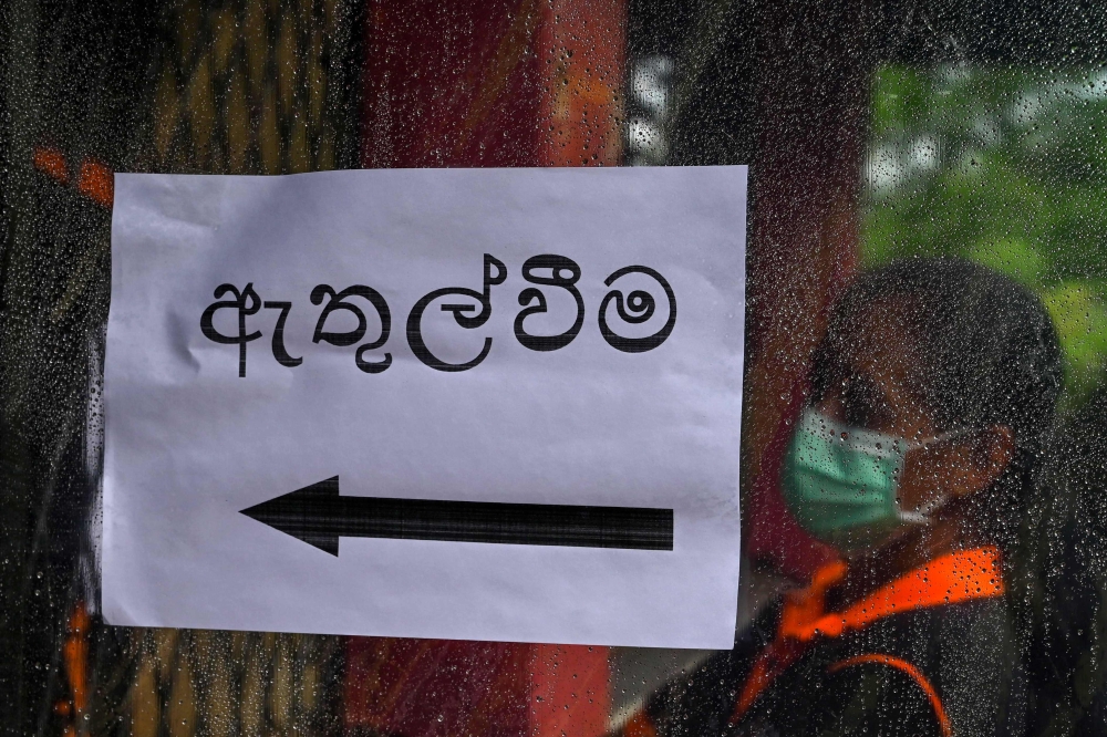 An election official stands to enter a polling station ahead of a mock election to test the guidelines implemented against the COVID-19 coronavirus in Ingiriya of Kalutara District in Western Province on June 14, 2020. AFP / LAKRUWAN WANNIARACHCHI